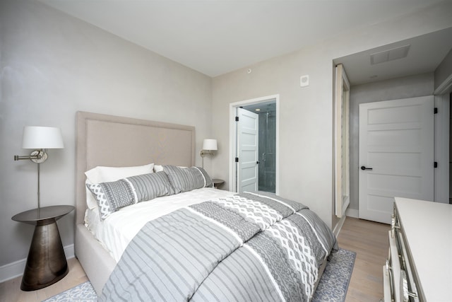 bedroom featuring ensuite bathroom and light hardwood / wood-style floors