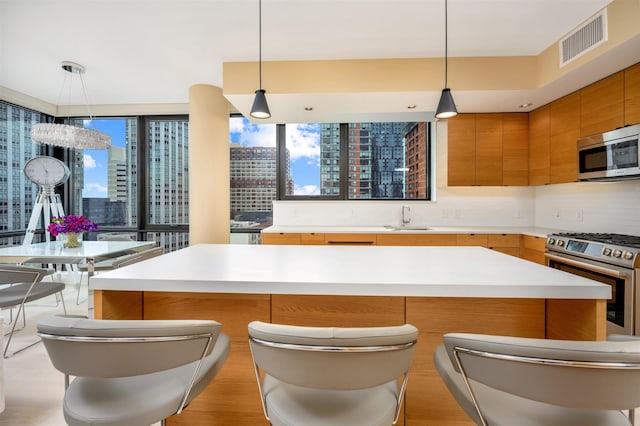 kitchen featuring sink, backsplash, stainless steel appliances, and hanging light fixtures