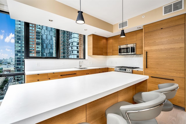 kitchen featuring pendant lighting, a kitchen bar, stainless steel appliances, tasteful backsplash, and sink