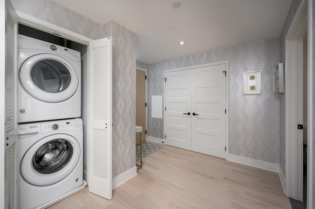 laundry room with stacked washer and dryer and light wood-type flooring