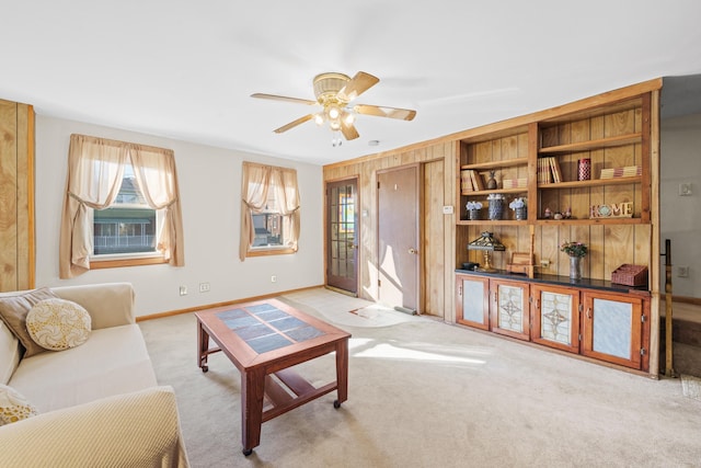 carpeted living room with wooden walls and ceiling fan