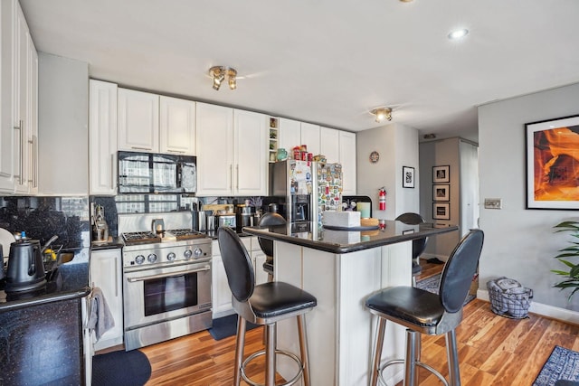 kitchen with white cabinets, stainless steel appliances, a breakfast bar area, and light hardwood / wood-style floors