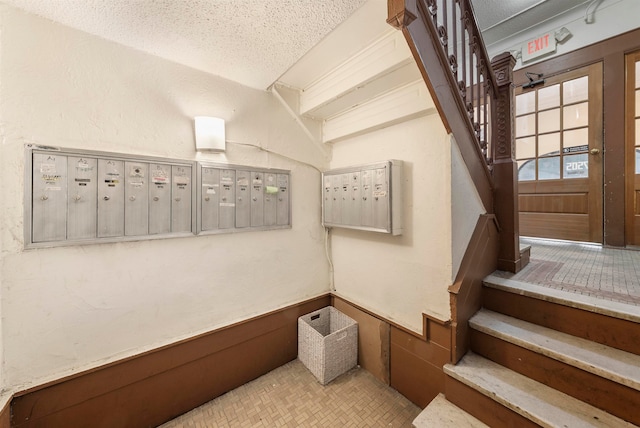 stairway featuring a textured ceiling and mail boxes