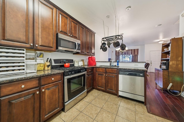 265 Custer Ave Unit 103, Jersey City, NJ 07305 - kitchen featuring stainless steel appliances, a peninsula, dark stone countertops, a chandelier, and light tile patterned floors