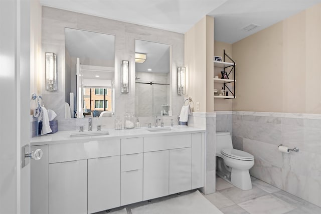 full bathroom with toilet, a sink, visible vents, tile walls, and double vanity