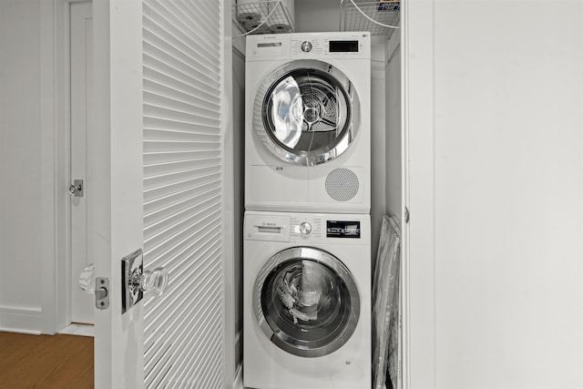 laundry area featuring stacked washer / drying machine, laundry area, and wood finished floors