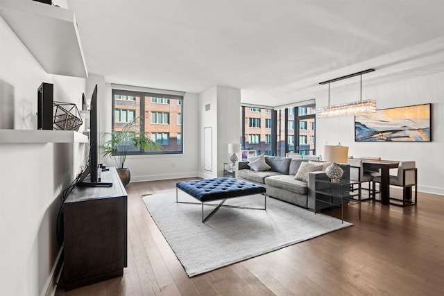 living area with baseboards, dark wood-type flooring, and a wealth of natural light