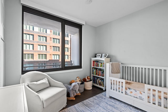 bedroom featuring a nursery area, multiple windows, and wood finished floors