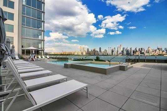 view of pool with a water view, a patio area, and a view of city