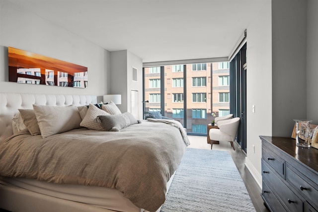 bedroom featuring visible vents, baseboards, wood finished floors, access to exterior, and expansive windows