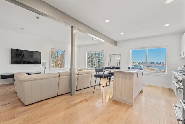 kitchen with light countertops, open floor plan, white cabinets, a kitchen island, and a kitchen bar