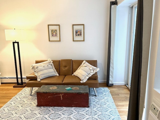 living area featuring baseboard heating, baseboards, and wood finished floors