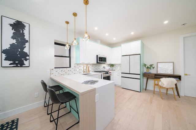 166 Steuben St Unit 1A, Jersey City, NJ 07302 - kitchen featuring white appliances, a peninsula, decorative backsplash, a kitchen bar, and light wood-style floors