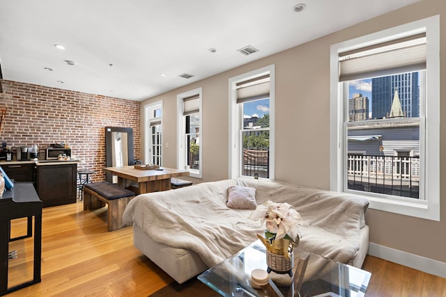 interior space featuring light hardwood / wood-style flooring, brick wall, and plenty of natural light