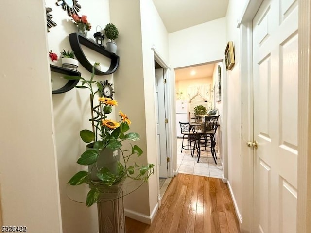 corridor with light wood-type flooring and baseboards