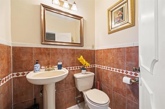 bathroom featuring toilet and tile walls