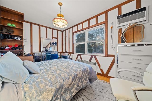 bedroom with radiator heating unit, light hardwood / wood-style flooring, and a wall unit AC