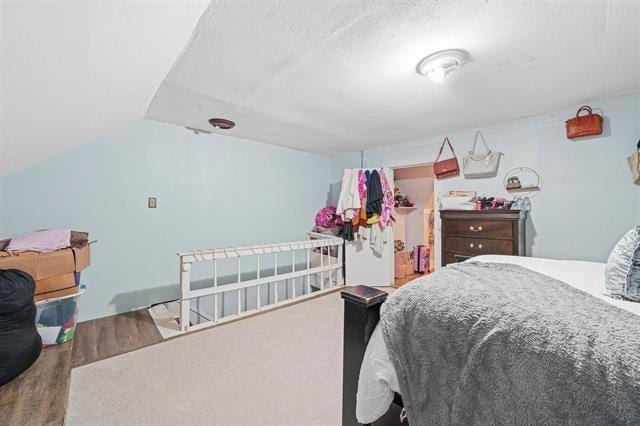 bedroom with vaulted ceiling, hardwood / wood-style floors, and a textured ceiling