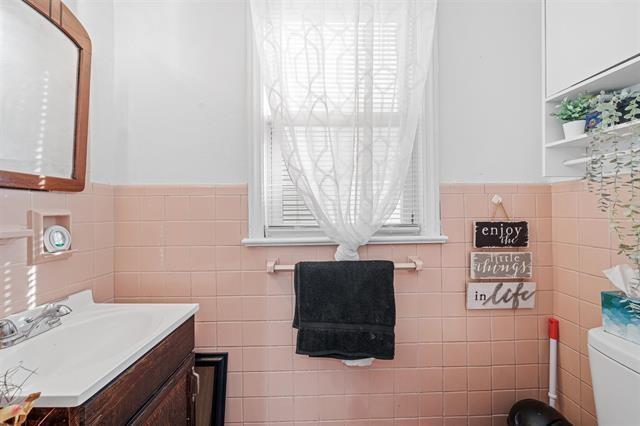 bathroom featuring vanity, toilet, and tile walls