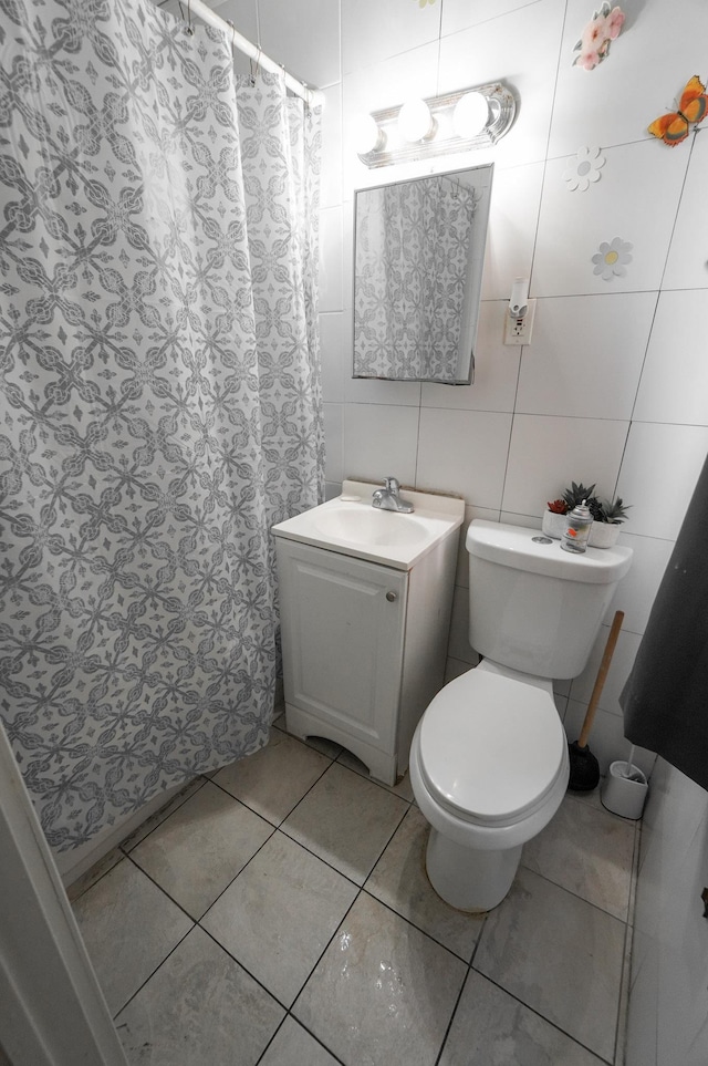 bathroom featuring vanity, tile patterned floors, tile walls, and toilet