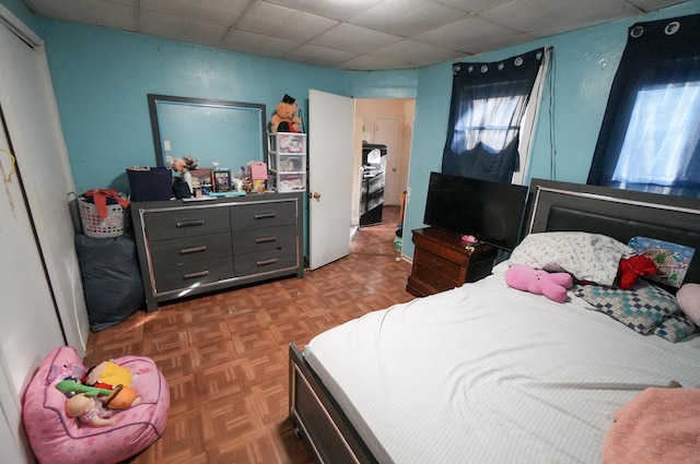 bedroom featuring a drop ceiling and dark parquet flooring