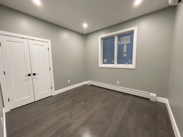 spare room featuring dark wood-style floors, baseboards, and baseboard heating