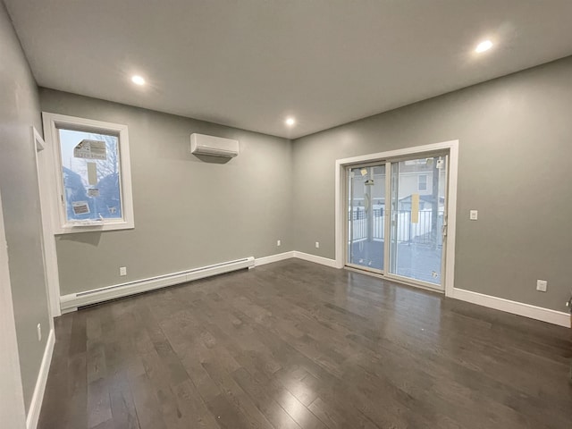 spare room featuring a baseboard heating unit, baseboards, dark wood-style flooring, and a wall mounted AC