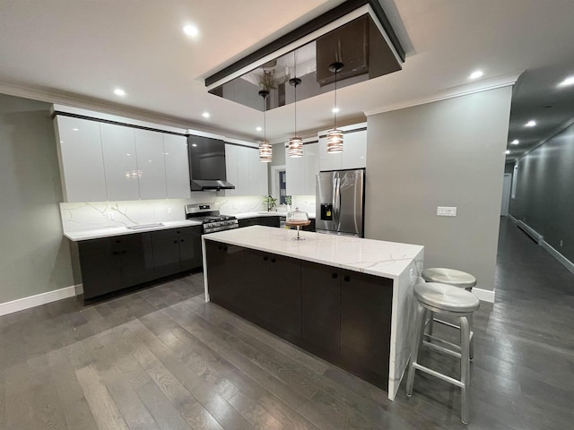 kitchen with stainless steel appliances, a large island, white cabinetry, wall chimney exhaust hood, and modern cabinets