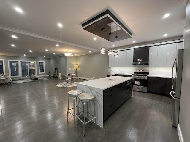 kitchen with a center island, appliances with stainless steel finishes, modern cabinets, wall chimney exhaust hood, and dark wood-style flooring