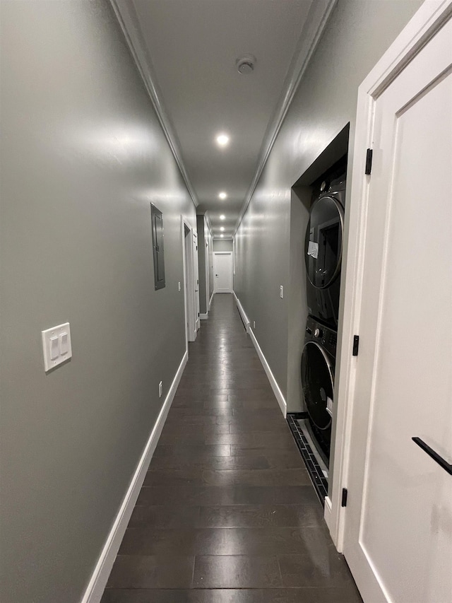 hall with ornamental molding, electric panel, dark wood finished floors, stacked washer / dryer, and baseboards