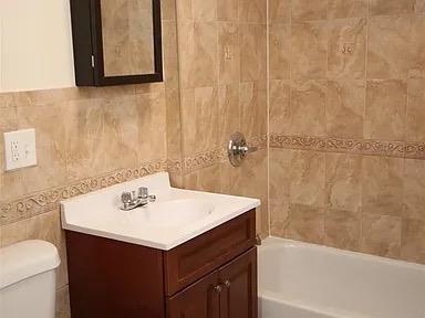 bathroom with vanity, toilet, and tile walls