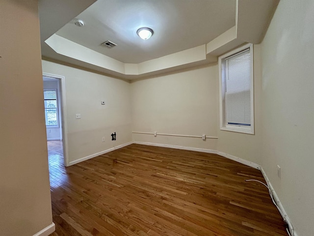 empty room with dark hardwood / wood-style flooring and a raised ceiling