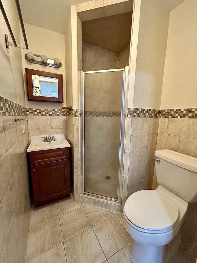 bathroom featuring tile patterned floors, toilet, vanity, a shower with shower door, and tile walls