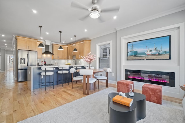 living room featuring ornamental molding, sink, ceiling fan, and light hardwood / wood-style flooring