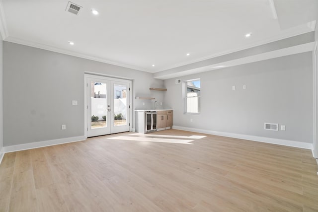 unfurnished living room with wine cooler, a wealth of natural light, french doors, and light wood-type flooring