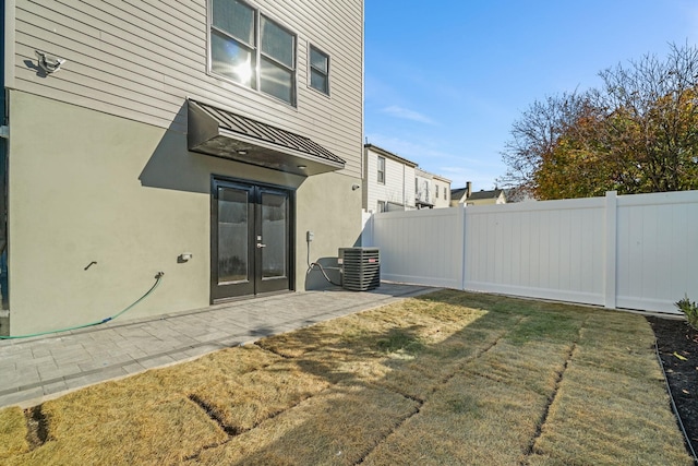 rear view of property with cooling unit, a yard, and a patio area