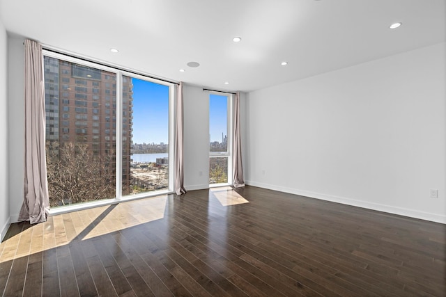 5 Washington Pl, Cliffside Park, NJ 07010 - empty room featuring a water view, dark wood-style flooring, baseboards, recessed lighting, and expansive windows