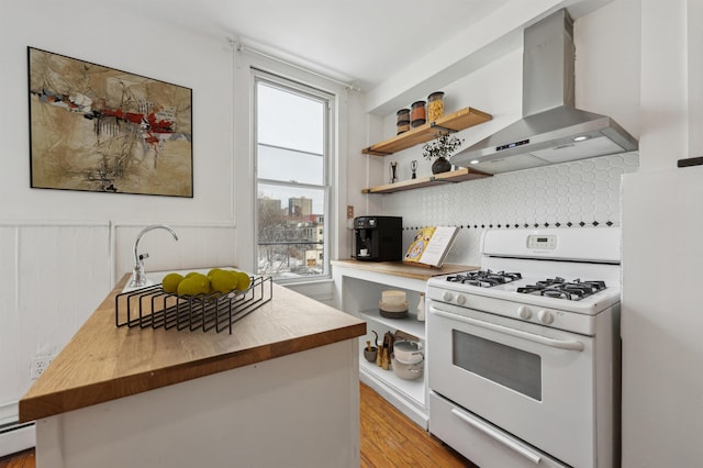 kitchen featuring white appliances, wall chimney range hood, wood counters, and open shelves