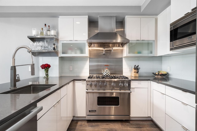 kitchen with wall chimney range hood, white cabinetry, a sink, dark wood finished floors, and stainless steel appliances