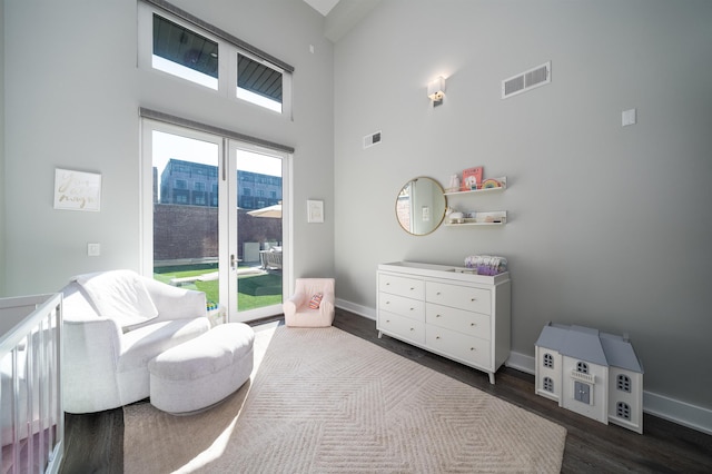 living area featuring visible vents, baseboards, a towering ceiling, and dark wood-style floors