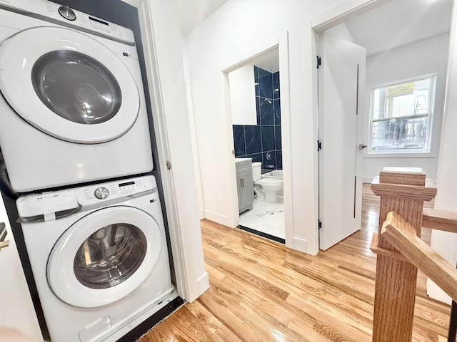 clothes washing area featuring stacked washer and dryer and light wood-style floors