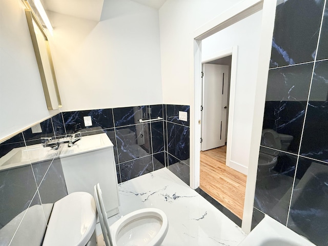 full bath featuring toilet, vanity, tile walls, and wood finished floors