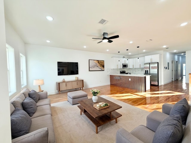 living area with light wood-style floors, recessed lighting, visible vents, and baseboards