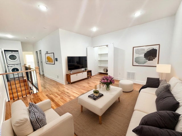 living room with stacked washer and clothes dryer, light wood finished floors, recessed lighting, visible vents, and baseboards