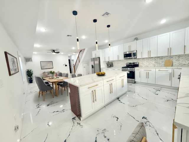 kitchen with visible vents, white cabinets, open floor plan, decorative light fixtures, and stainless steel appliances