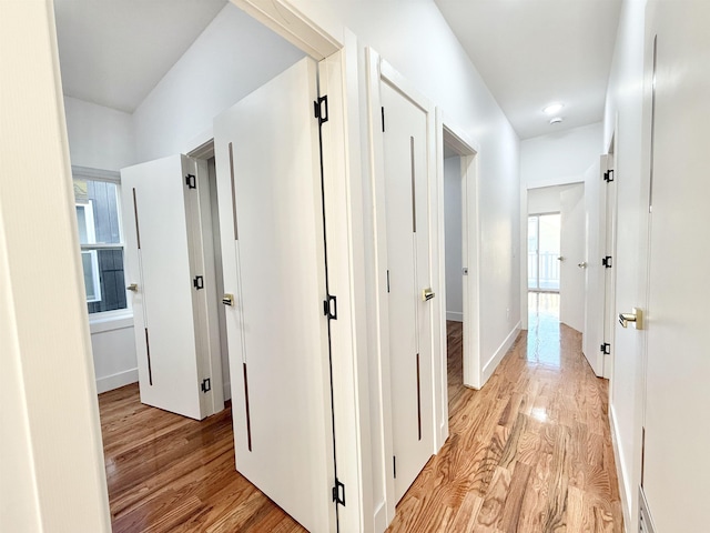 corridor with light wood-style flooring and baseboards