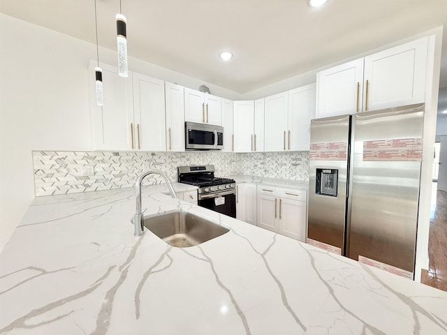 kitchen featuring decorative light fixtures, stainless steel appliances, white cabinets, a sink, and light stone countertops