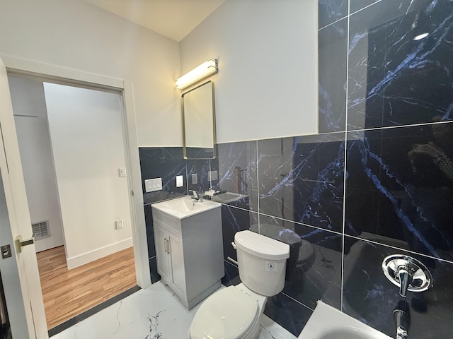 full bath featuring a bathtub, marble finish floor, visible vents, toilet, and vanity