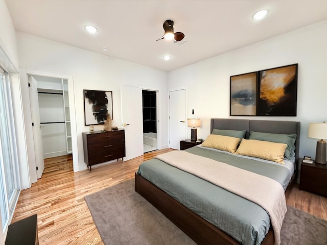 bedroom featuring light wood-type flooring, a walk in closet, and recessed lighting