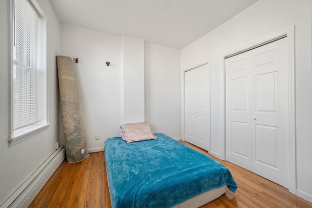 bedroom with hardwood / wood-style flooring and a baseboard heating unit